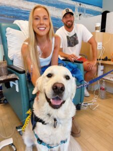 Tanner smiling with a Purdy, the therapy dog, during chemotherapy.